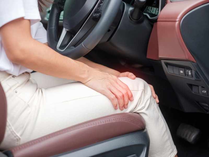 conductor tocándose la rodilla por dolor al manejar
